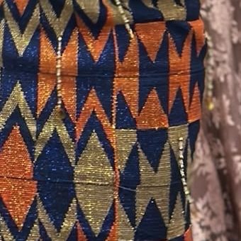 Close-up of a mermaid gown in orange, blue and gold kente