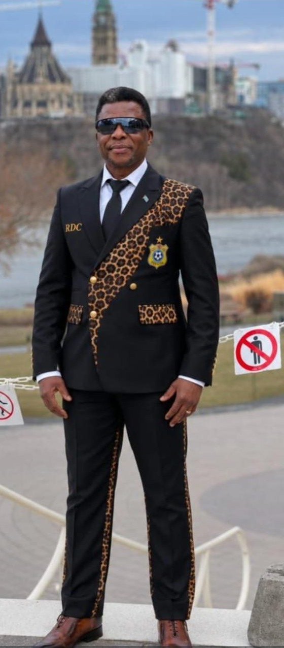 Black suit with braid trim and leopard-print panels, worn in front of Parliament Hill